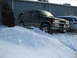 1998 Chevrolet Tahoe - This SUV is partially buried in a large snowbank, with its tires struggling for traction.