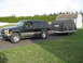 1998 Chevrolet Tahoe - A black Chevrolet Tahoe from the mid-1990s is seen from the side, towing a covered trailer.