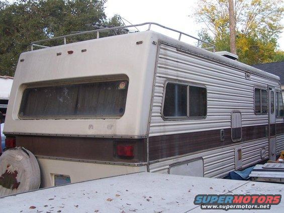 Motorhome rear with large window, roof rack, and spare tire cover