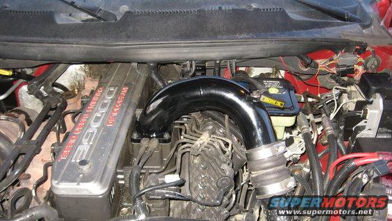 Dodge 5.9L Cummins Turbo Diesel engine with aftermarket intake pipe. Shows engine block and some wiring