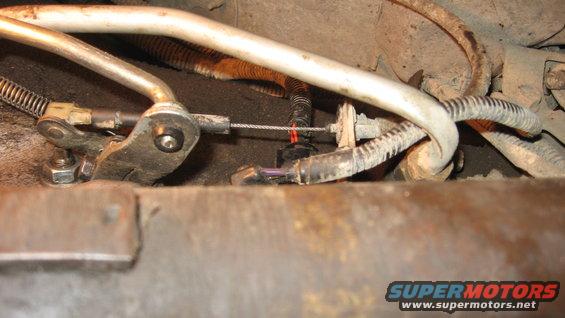 Close-up of a throttle cable linkage with springs and metal housing