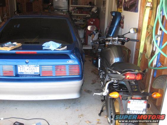 Blue Ford Mustang and a dark gray Yamaha motorcycle parked in a garage