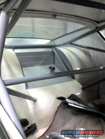 Interior view of a car with a roll cage, showing seats and rear paneling