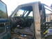 1984 Ford Bronco II - The interior of a heavily modified off-road vehicle, a roll cage and worn seats, is visible from the side.