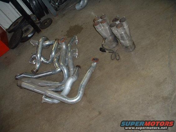 Exhaust headers and mufflers laid out on a concrete floor