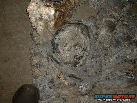 Close-up of a corroded tire and rim assembly on the ground