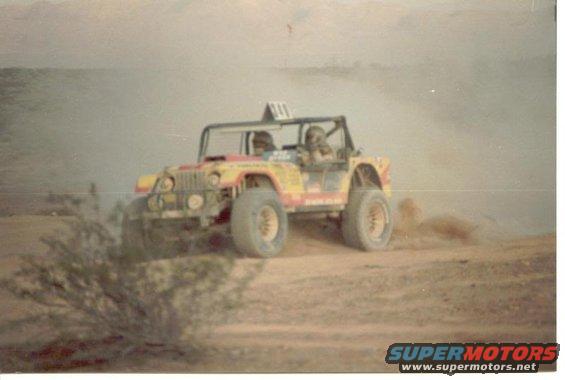 1994 Jeep YJ off-roading, kicking up dust, with two occupants
