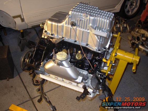 engine on yellow stand, car body in background