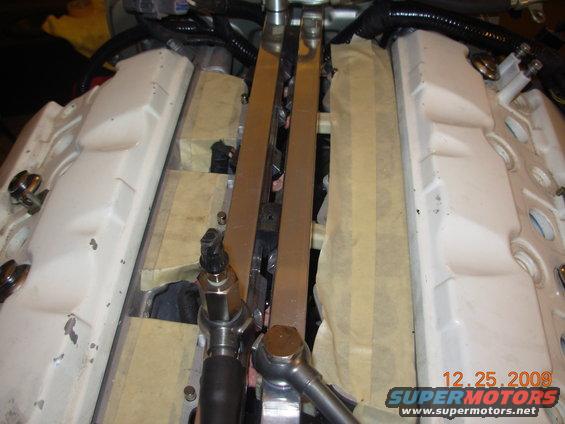 Close-up of engine components, possibly fuel injectors and intake manifold, with masking tape applied