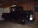1949 Ford F1 - A black pickup truck is parked inside a garage with the door open.