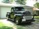 1949 Ford F1 - This black Ford pickup truck, likely a 1948 model, is parked in front of a garage.