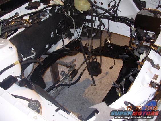 Engine bay with wiring and frame components visible, undergoing repair