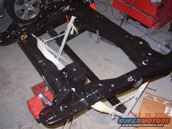 Black painted vehicle frame assembly on a stand, with a wheel visible