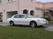2002 Lincoln Town Car - A white 2002 Lincoln Town Car is seen from a three-quarter front view, parked on a grassy area in front of a residential building.