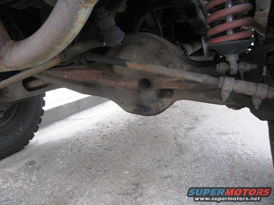 Close-up of a vehicle's rear axle, differential housing, and suspension components, including a coil spring
