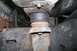 1992 Ford C-350 (Centurion Conversions) - Close-up of a body lift spacer on a heavily rusted vehicle frame and suspension components.