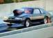 1990 Ford Mustang - A 1990 Ford Mustang drag car with a dragon decal on its hood scoop is captured in motion on a race track.