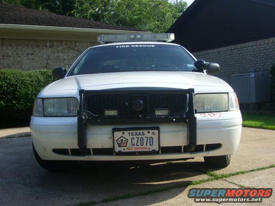 White 2003 Ford Crown Victoria police car with a black push bar, light bar, and Texas license plate CZ07D