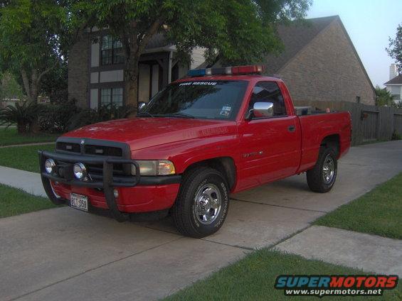 Red Dodge Ram pickup truck with "FIRE RESCUE" on windshield and emergency lights on roof