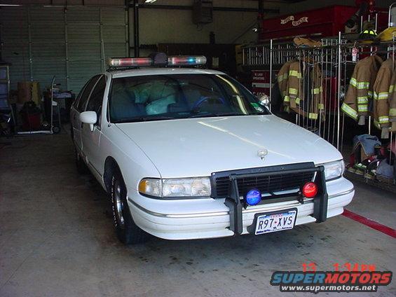 White police car with push bumper and light bar, parked indoors