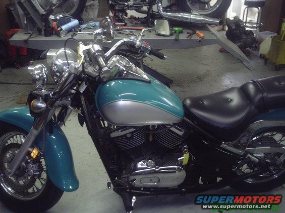 Teal and silver motorcycle side view, parked in a workshop