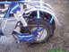 1970 Honda Trail - Close-up view of a blue motorcycle's rear wheel, suspension, and drivetrain components.