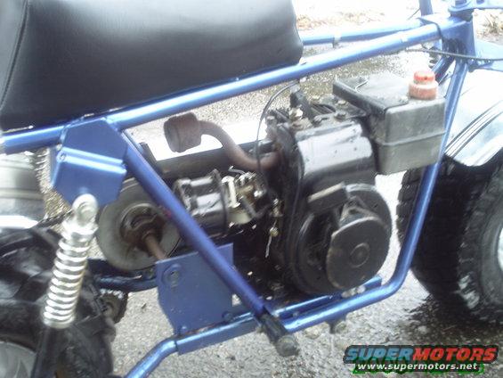Blue mini bike side view with engine and black seat. Text reads www.supermotors.net
