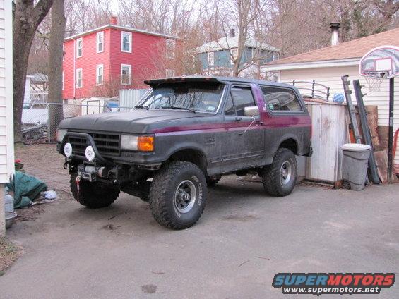 1989 Ford Bronco with aftermarket bumper, winch, and off-road tires parked in a driveway