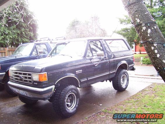 Dark gray 1988 Ford Bronco parked next to a blue truck