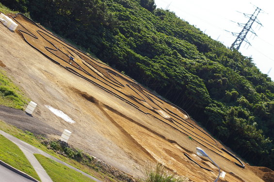RC track on a dirt hillside with trees and a power line tower in the background