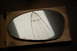 2002 BMW M3 - A cracked side mirror glass is shown resting on a cardboard box, with website text visible at the bottom.