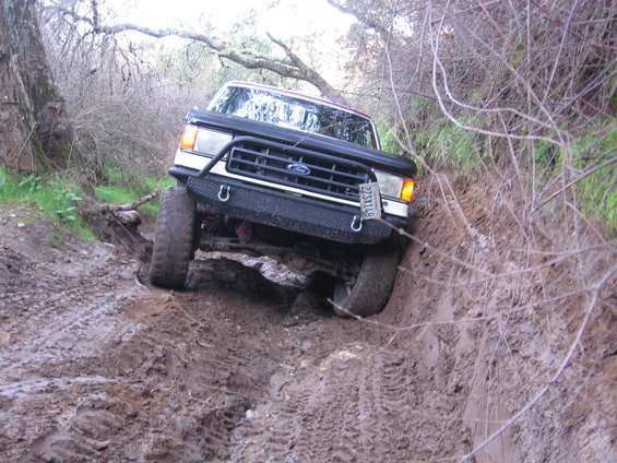 Ford Bronco navigating a muddy trail, tires digging into the dirt