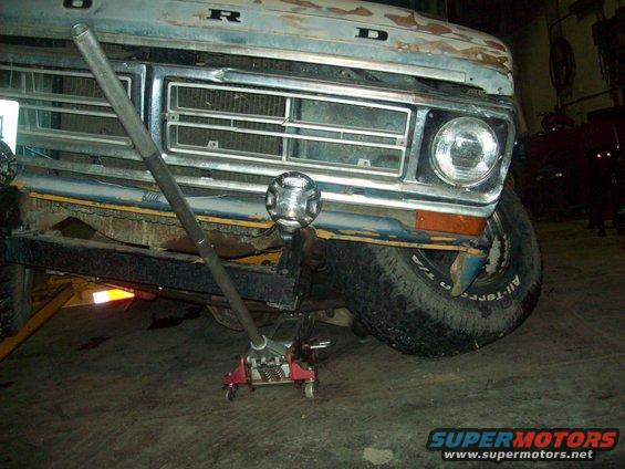 1971 Ford F-100 front end, grille, and headlight with a jack under the bumper