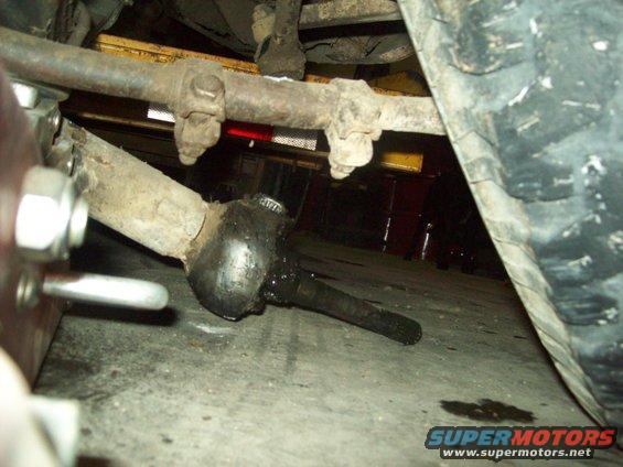 close-up of a vehicle's tie rod end and drag link, showing grease and wear