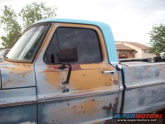 Side view of a rusty, two-tone blue and tan pickup truck with a light blue cab roof
