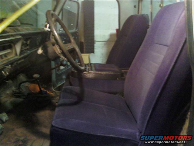Interior view of a truck, showing the steering wheel, dashboard, and purple seats