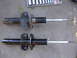 1992 Ford Taurus - A comparison of a used and a new car suspension strut is shown on a concrete surface.