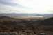 1991 Ford Bronco - Wide view of a desert landscape with mountains and a dry lake bed under a cloudy sky.