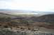 1991 Ford Bronco - A vast desert valley stretches out below , rocky hills under a hazy sky.