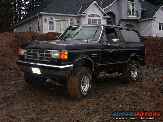 Black Ford Bronco with aftermarket wheels parked on a dirt mound