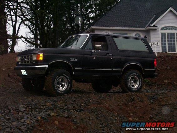Black Ford Bronco with aftermarket wheels and tires parked on a dirt incline