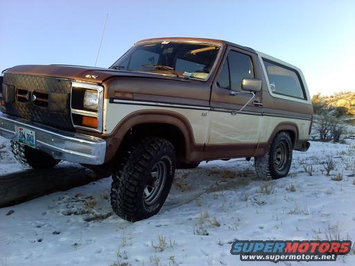 Brown and white Ford Bronco with aftermarket grille and off-road tires in snow