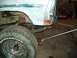 1971 Ford F-100 - Close-up of a rusty truck frame and tire being worked on in a garage.