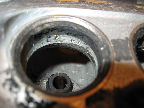 Close-up of a dirty engine cylinder head with carbon buildup around the valve seat