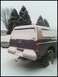 1996 Ford Bronco - A dark colored SUV with a camper shell is seen from the rear, covered in snow.