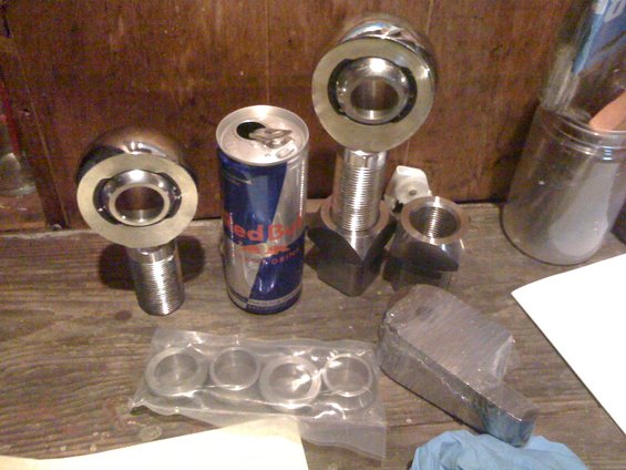 Metal suspension components and a Red Bull can on a wooden surface