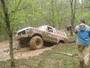 Muddy off-road vehicle on dirt path, trees in background