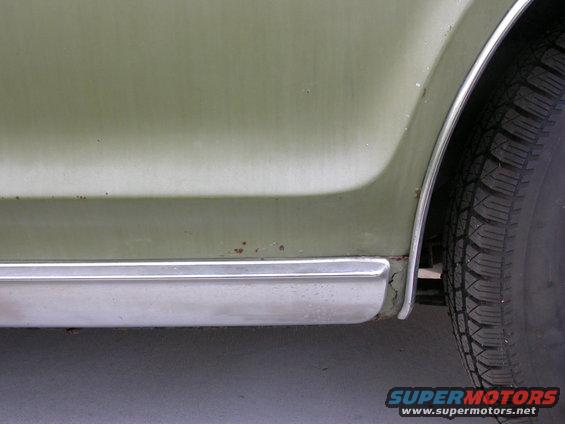 Green 1968 Mercury Cougar rear quarter panel and tire, showing rust spots and chrome trim