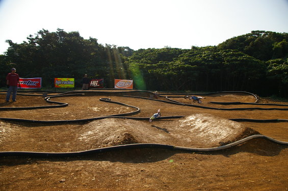 Remote control cars racing on a dirt track with trees in the background