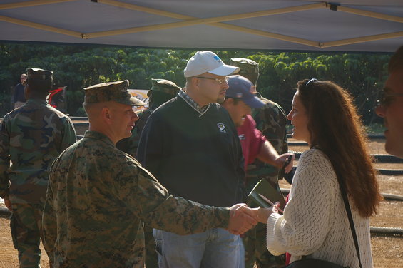 People in military uniforms and civilian clothes interacting under a tent